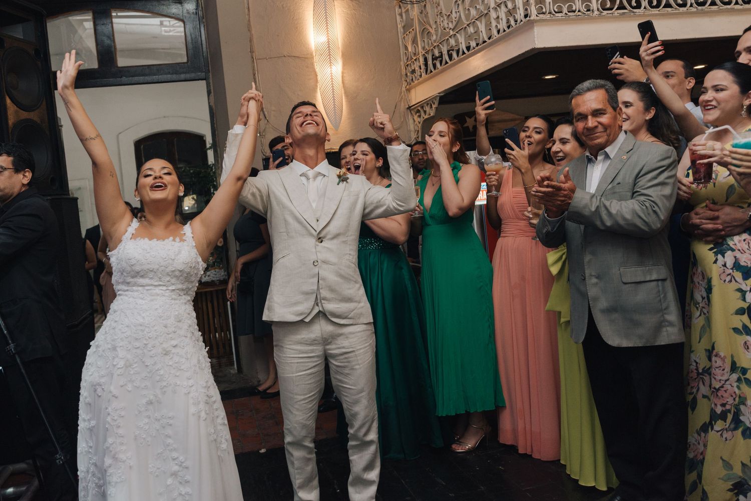 Wedding celebration with couple and guests cheering in a decorated venue.