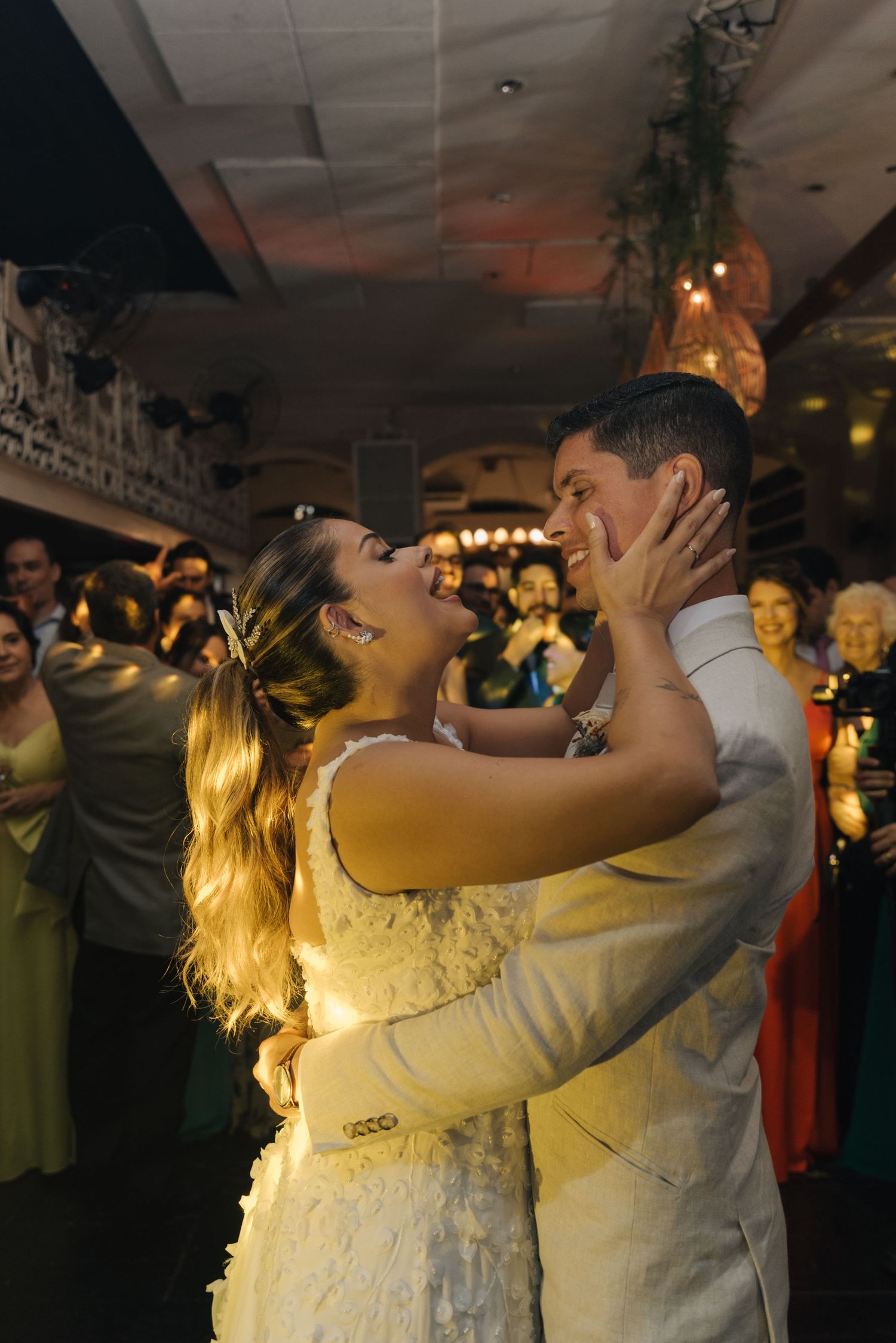 A bride and groom share a tender romantic dance moment at their wedding reception with ambient lighting.
