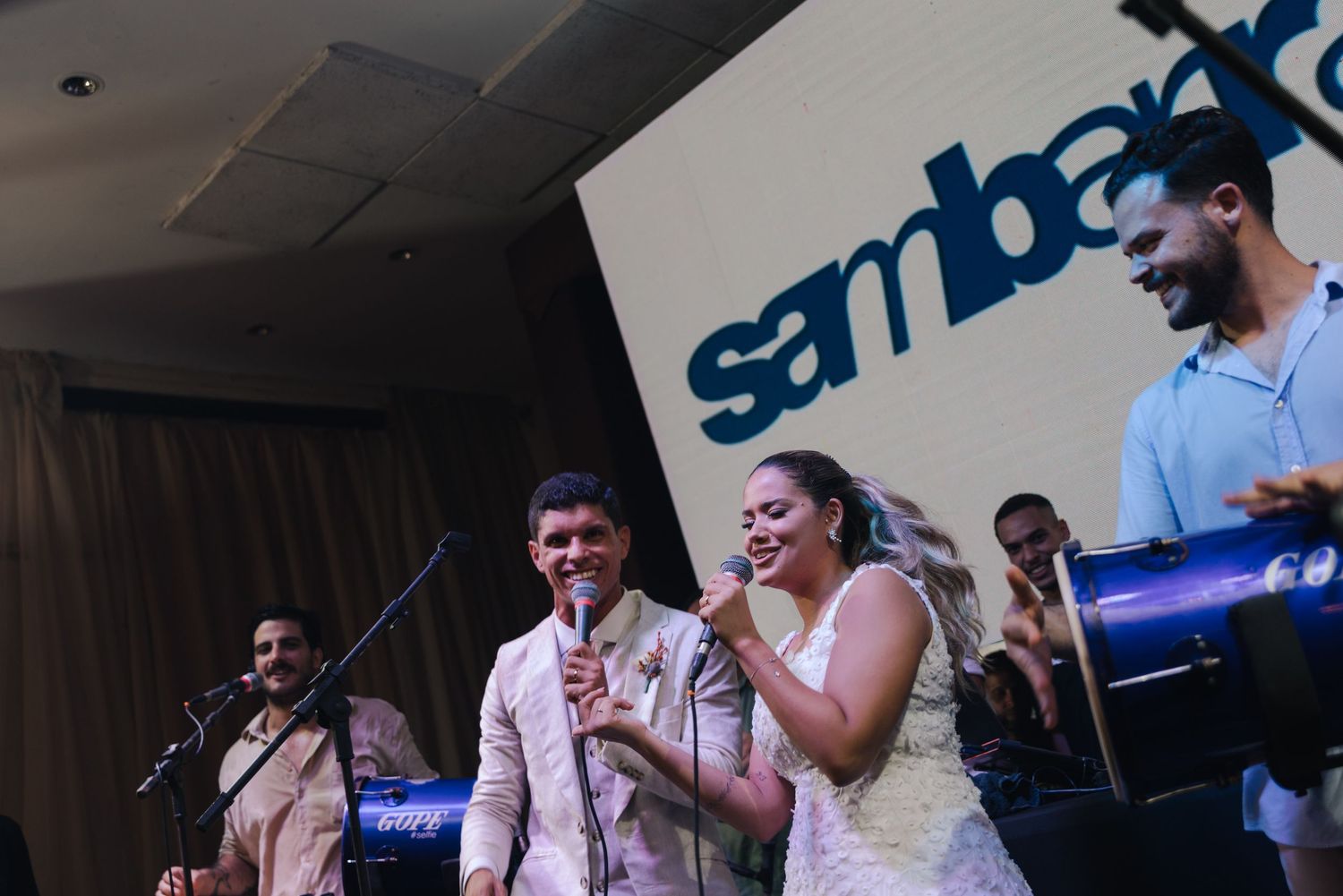 Live band performs at wedding reception with instruments and microphones on stage.