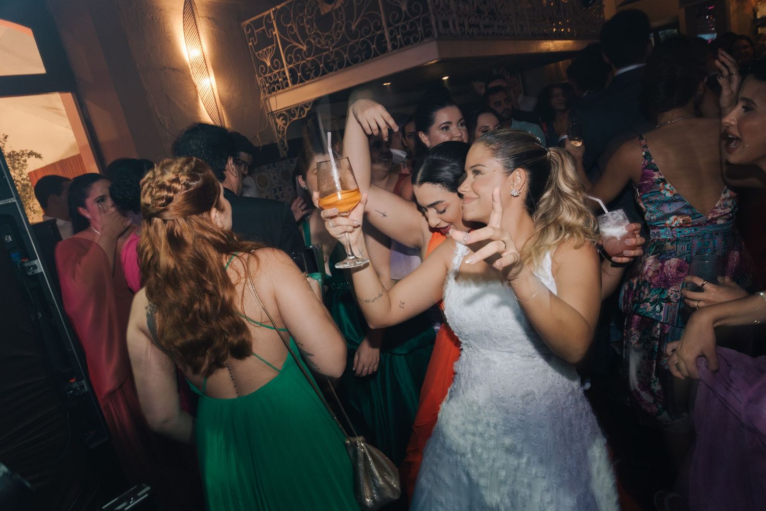 People dancing and celebrating at a wedding reception with atmospheric lighting.