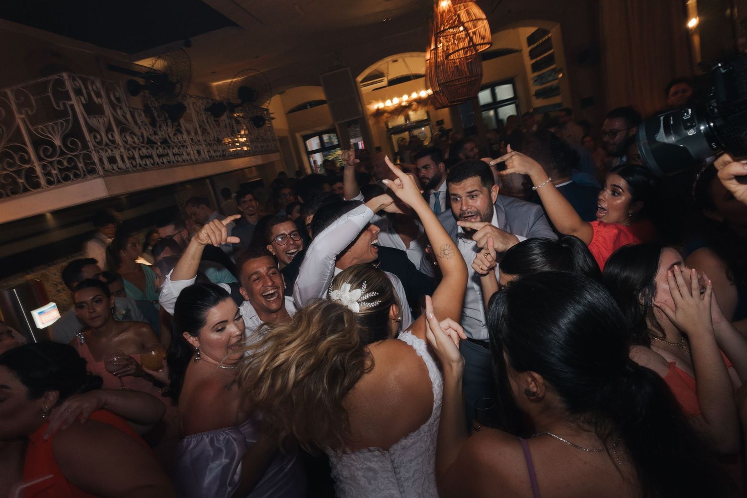 Crowded dance floor with guests celebrating around someone in a white dress.
