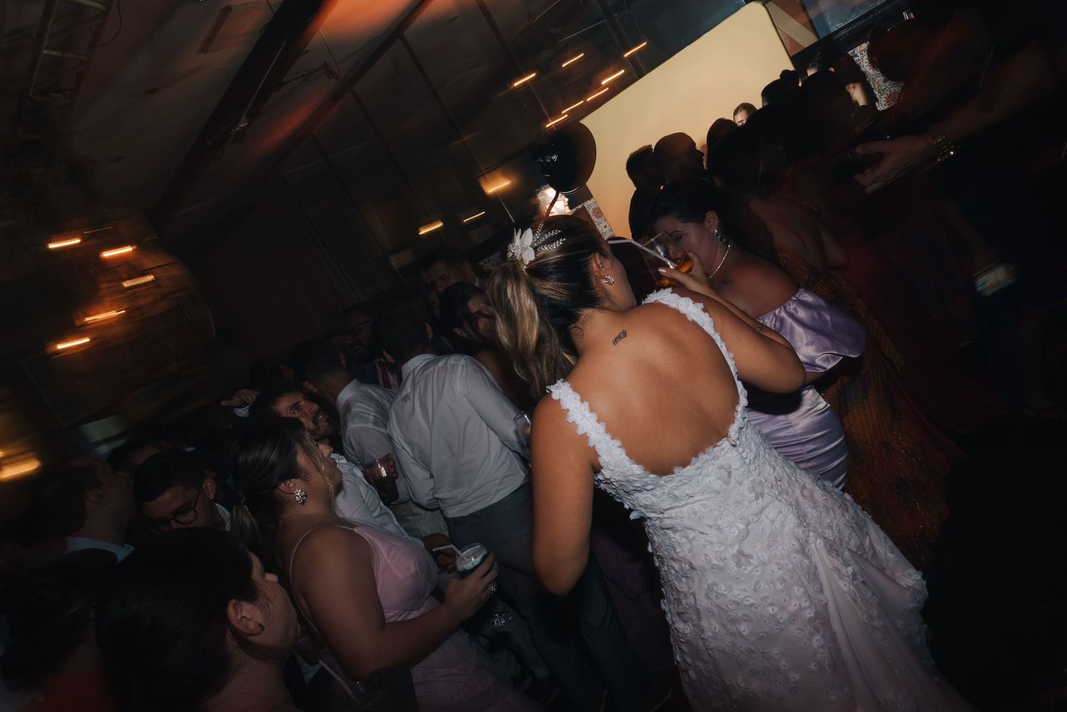 Dancing guests packed together on a dark dance floor at a wedding celebration.