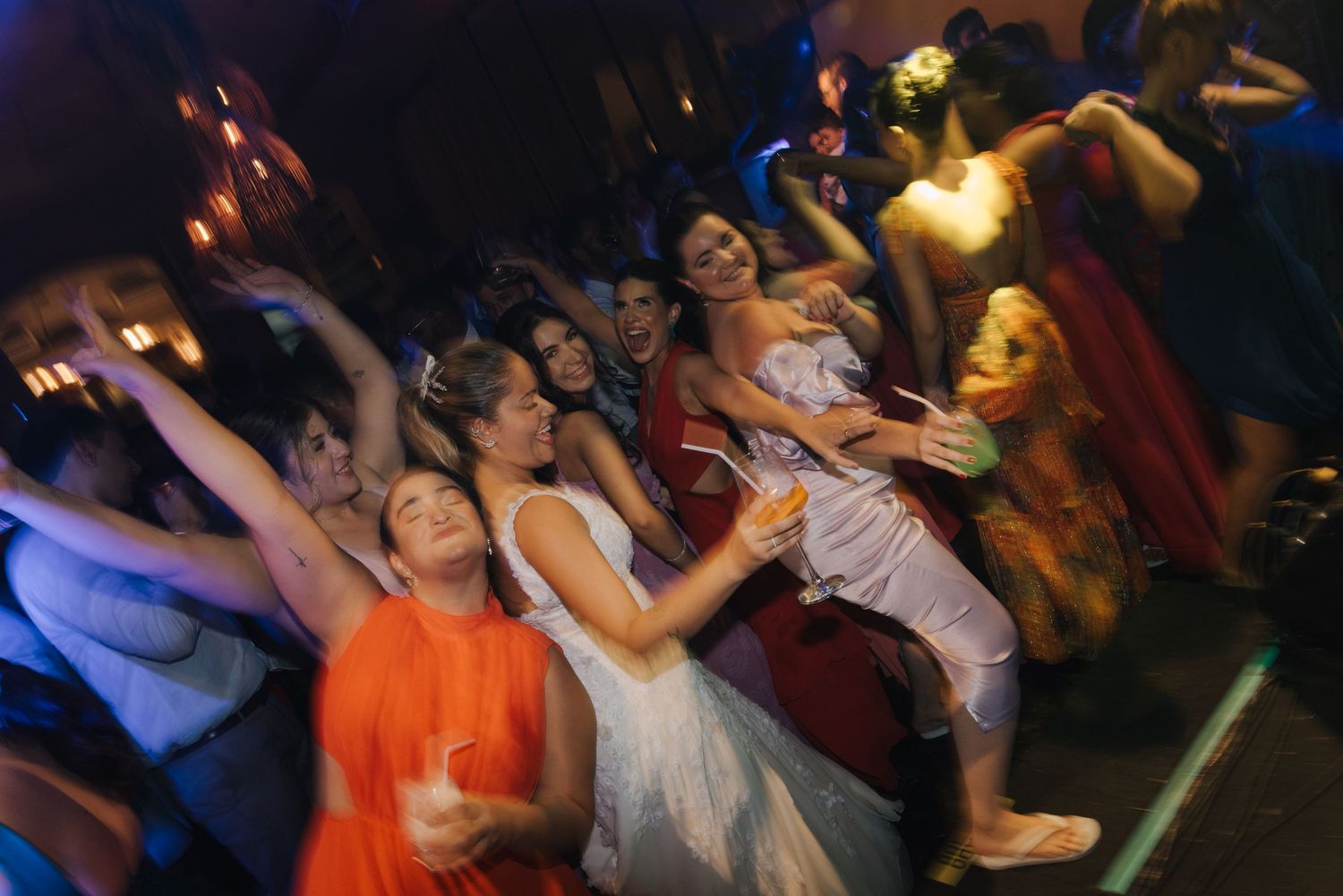 Blurred motion shot of wedding guests dancing energetically on the dance floor.
