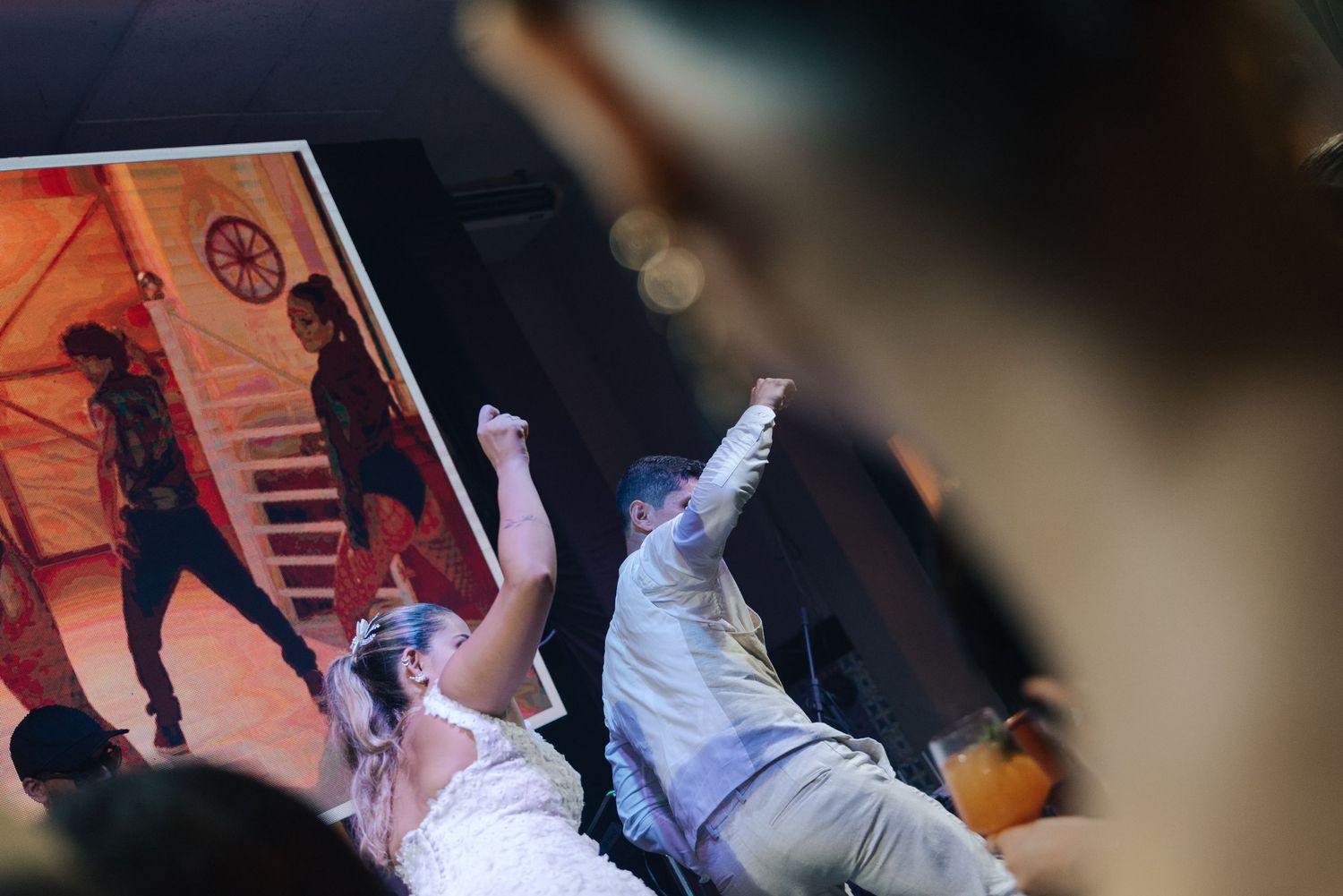 Dynamic shot of wedding attendees dancing with dramatic lighting and movement.