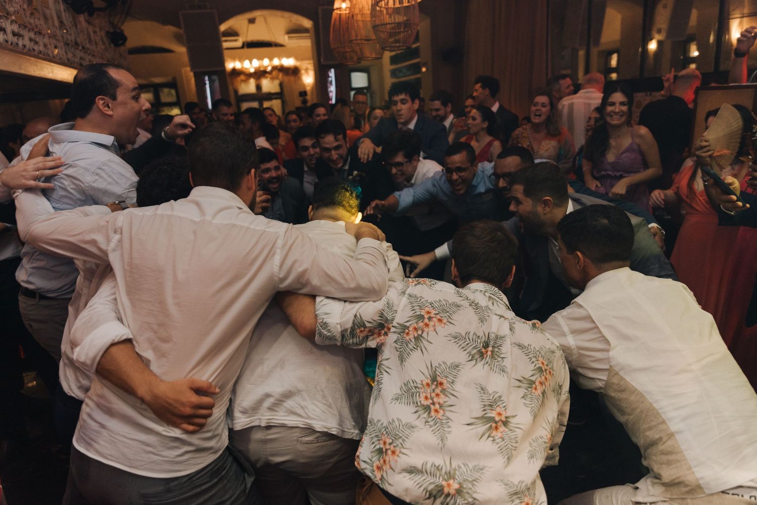 Wedding guests lean in for a group celebration photo at an indoor reception.