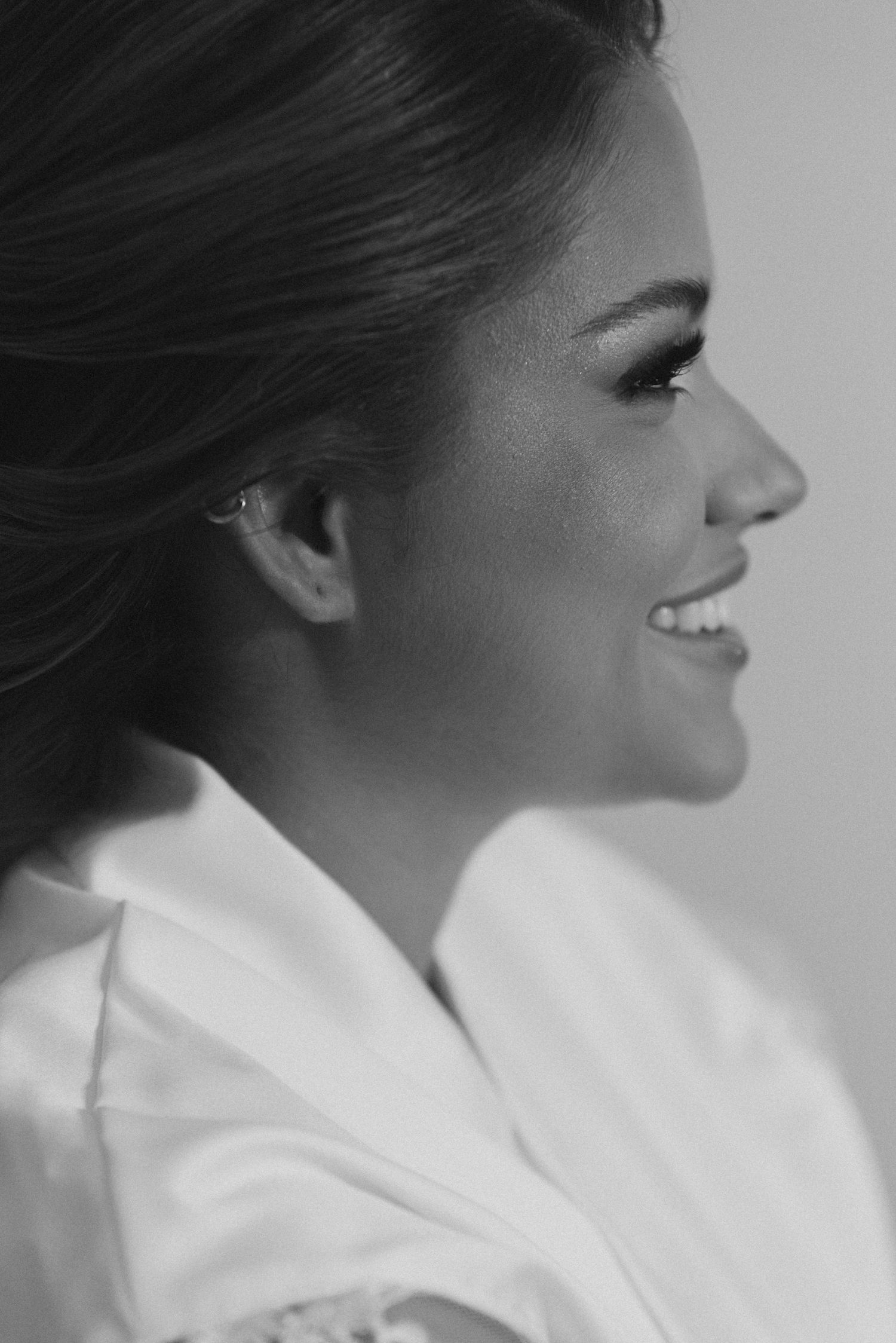 Black and white profile portrait of a smiling woman in a white collar wearing natural makeup.
