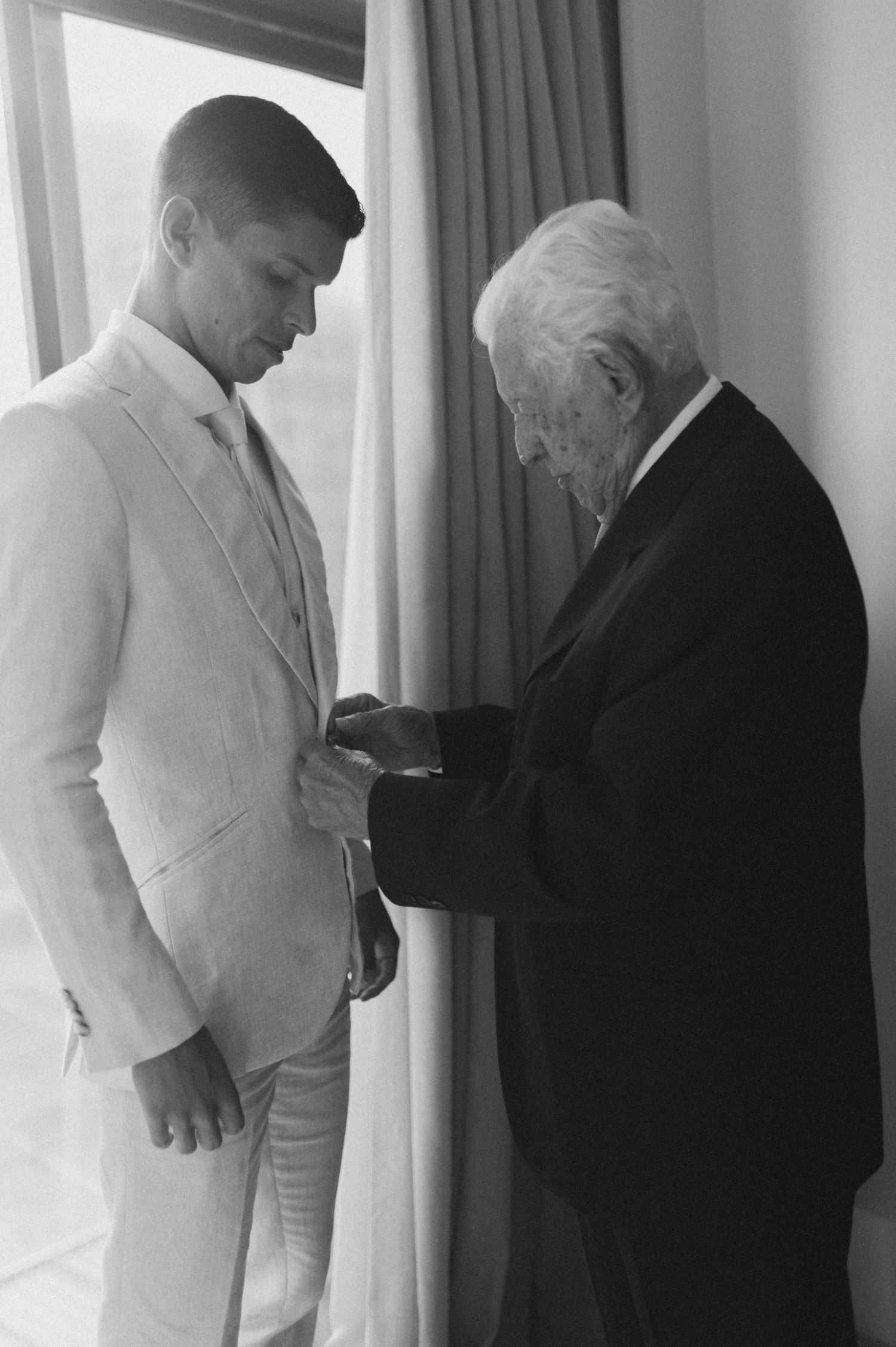 An intimate moment as an elderly person helps adjust a young person's formal attire.