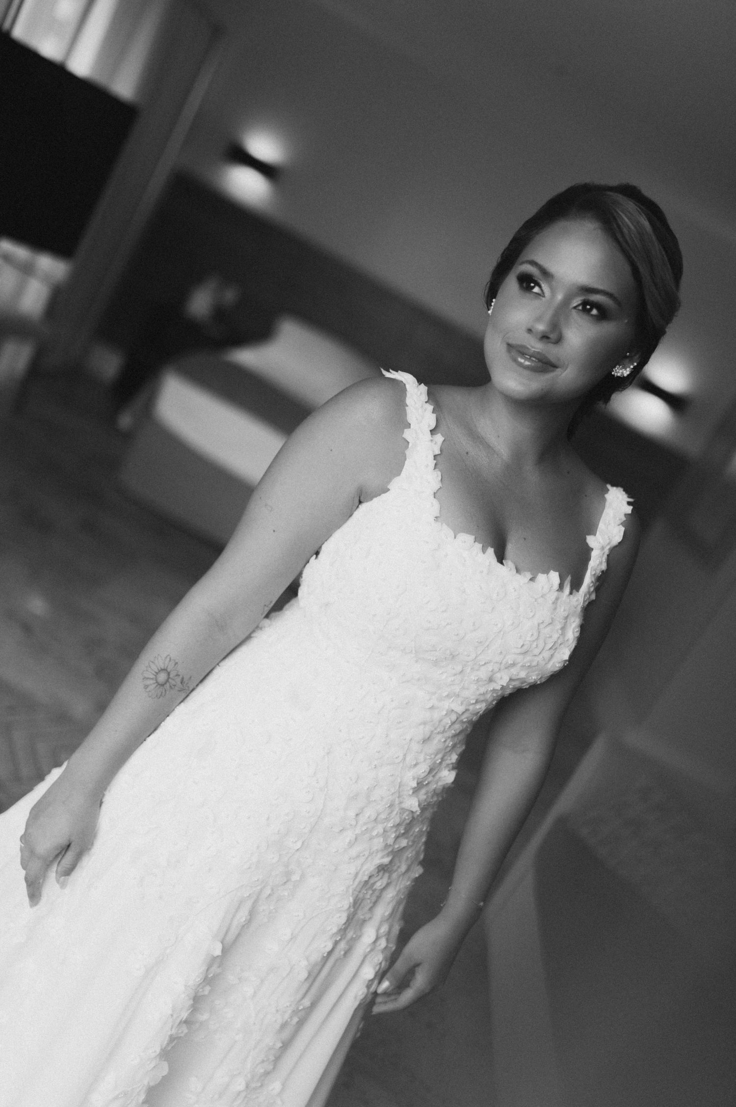 A bride in a classic lace wedding gown poses elegantly in black and white photography.