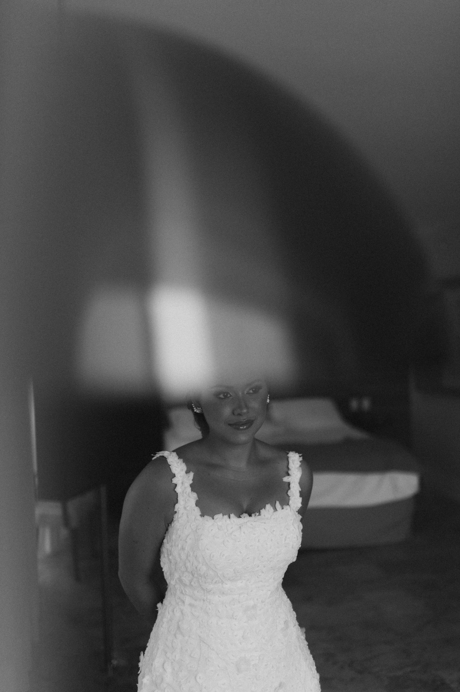 Artistic bridal portrait through blurred foreground showing bride in white lace gown.
