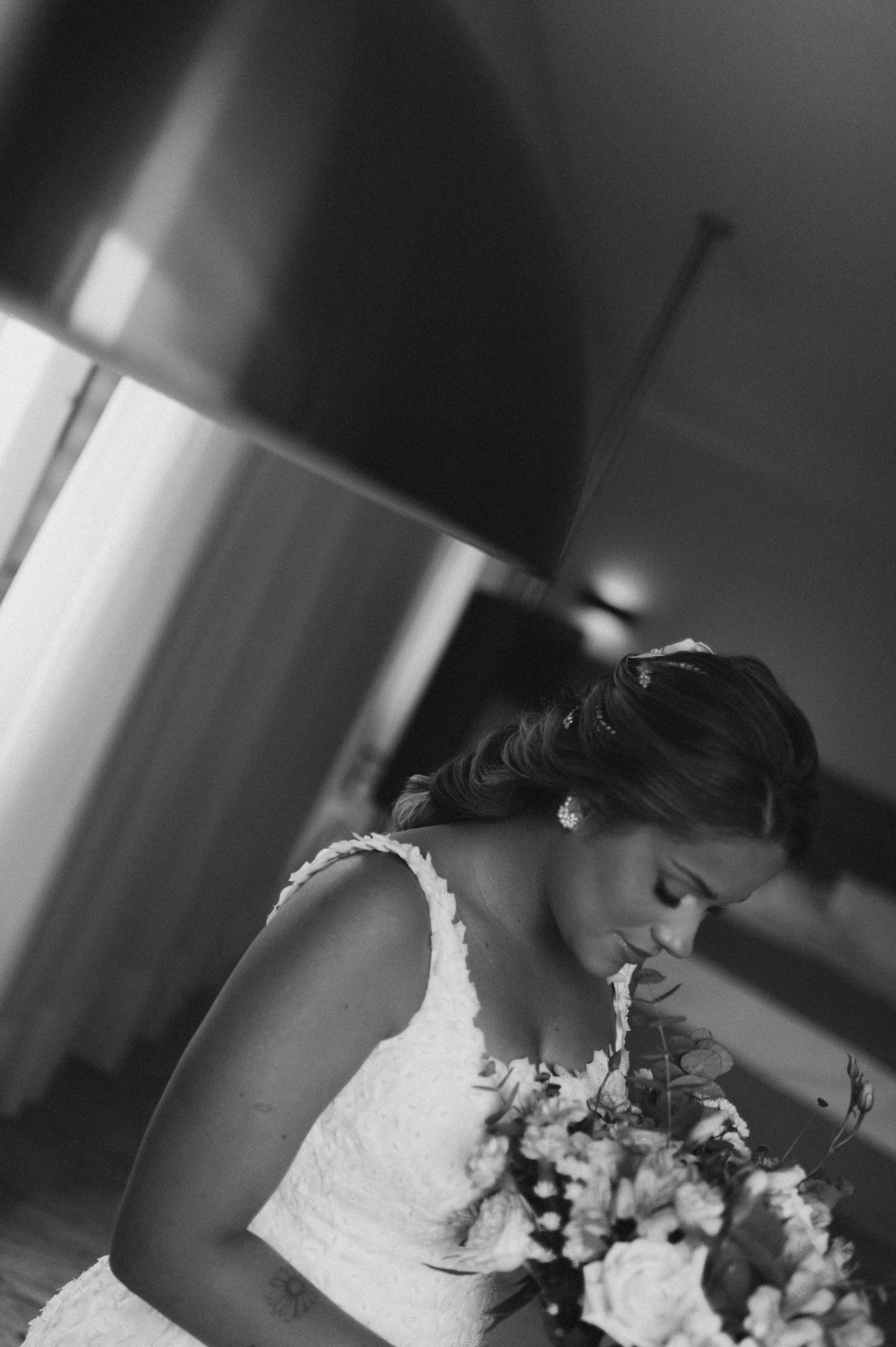 Intimate black and white photo of bride looking down at her bouquet.