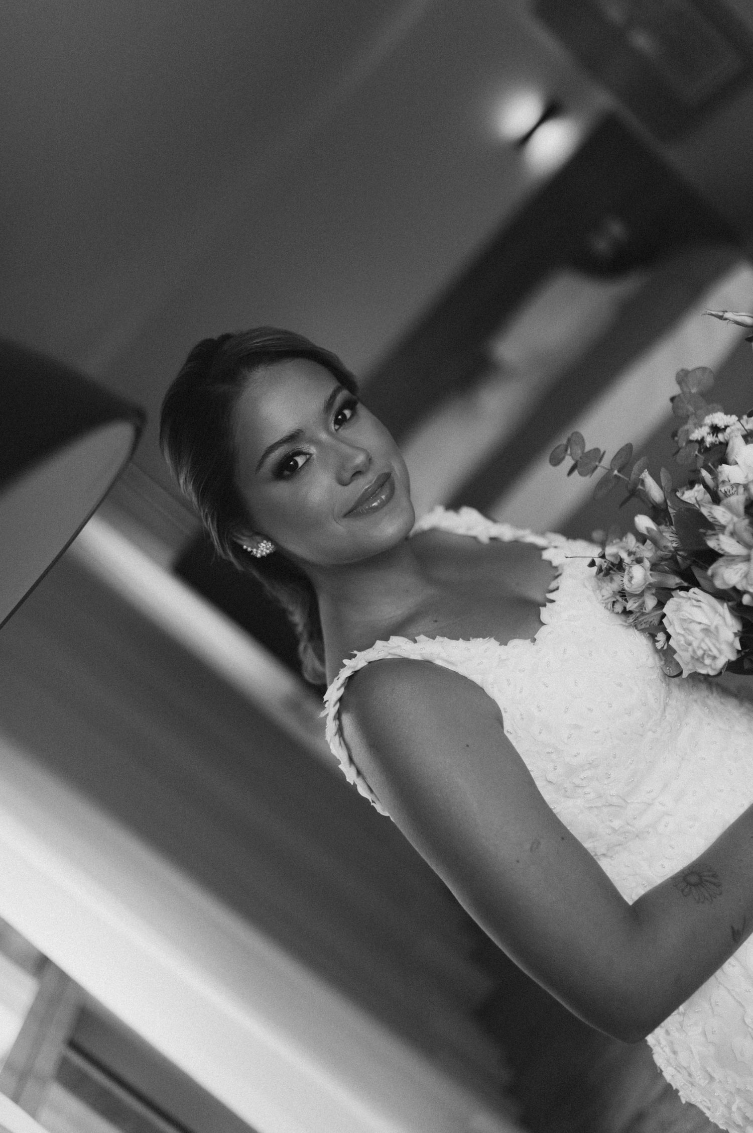 Side-lit bridal portrait showing bride with updo hairstyle holding wedding flowers.