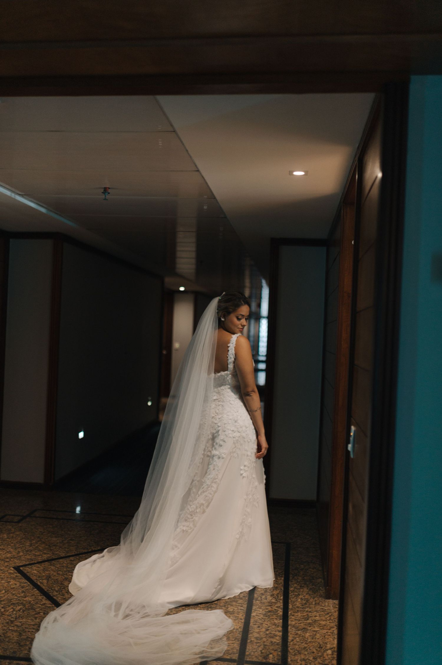 Full-length back view of bride in fitted lace wedding gown with trailing veil.