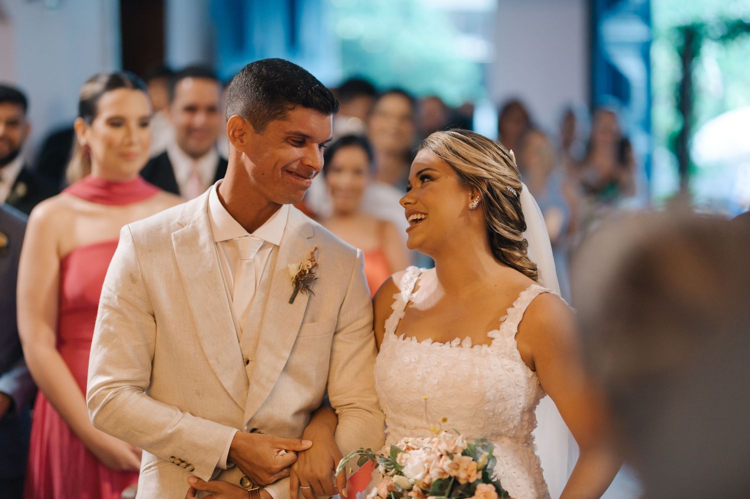 Couple shares joyful moment during wedding ceremony in front of wedding party.