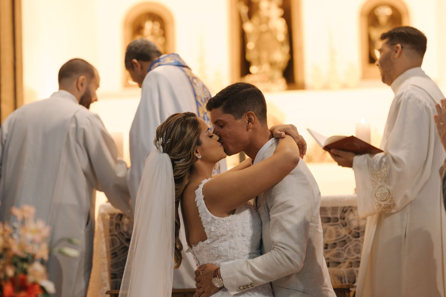 Newlyweds share romantic kiss during church wedding ceremony.