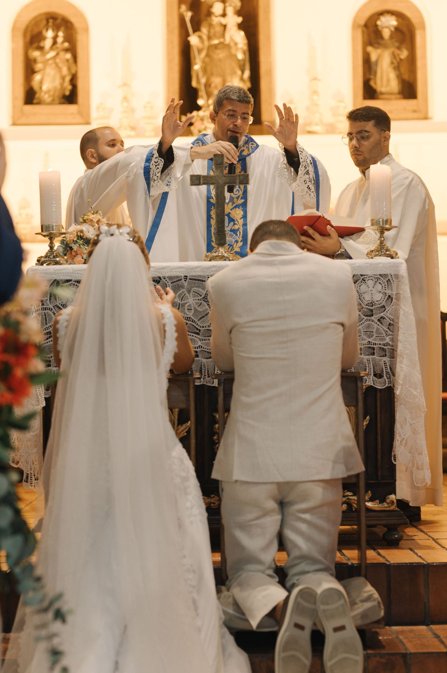 Priest performs wedding blessing ceremony at ornate church altar.
