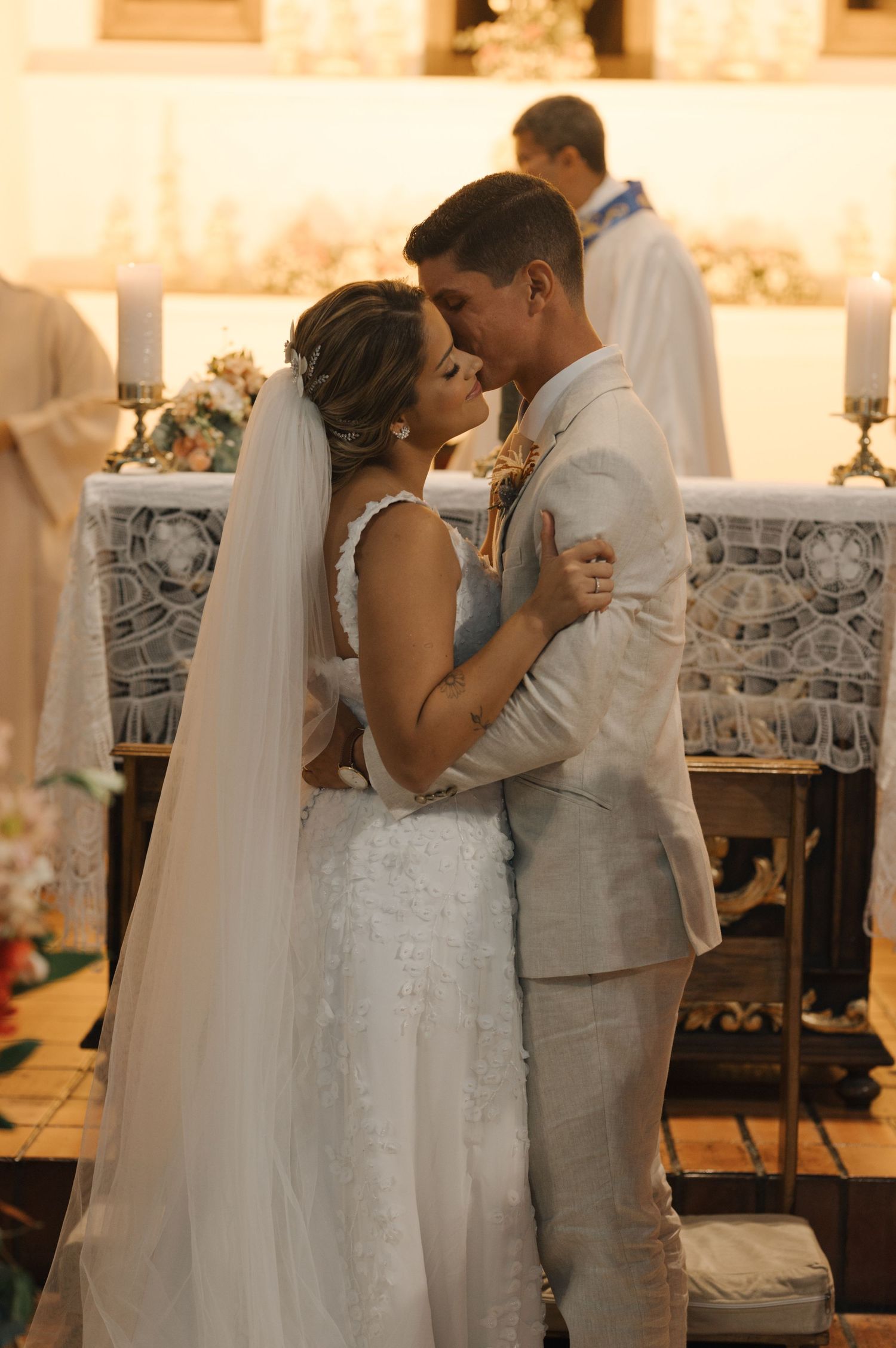 A tender moment between newlyweds sharing an intimate embrace during their wedding ceremony in a church.