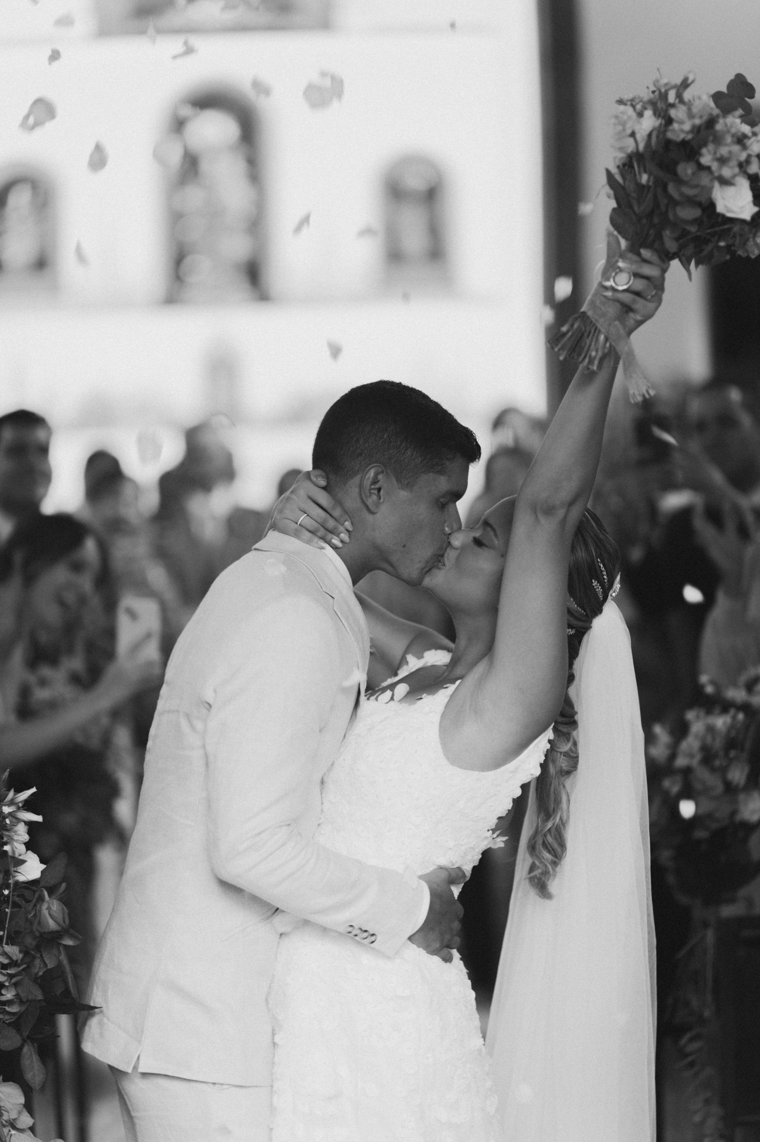 A romantic black and white photo of newlyweds sharing their first kiss as a married couple.