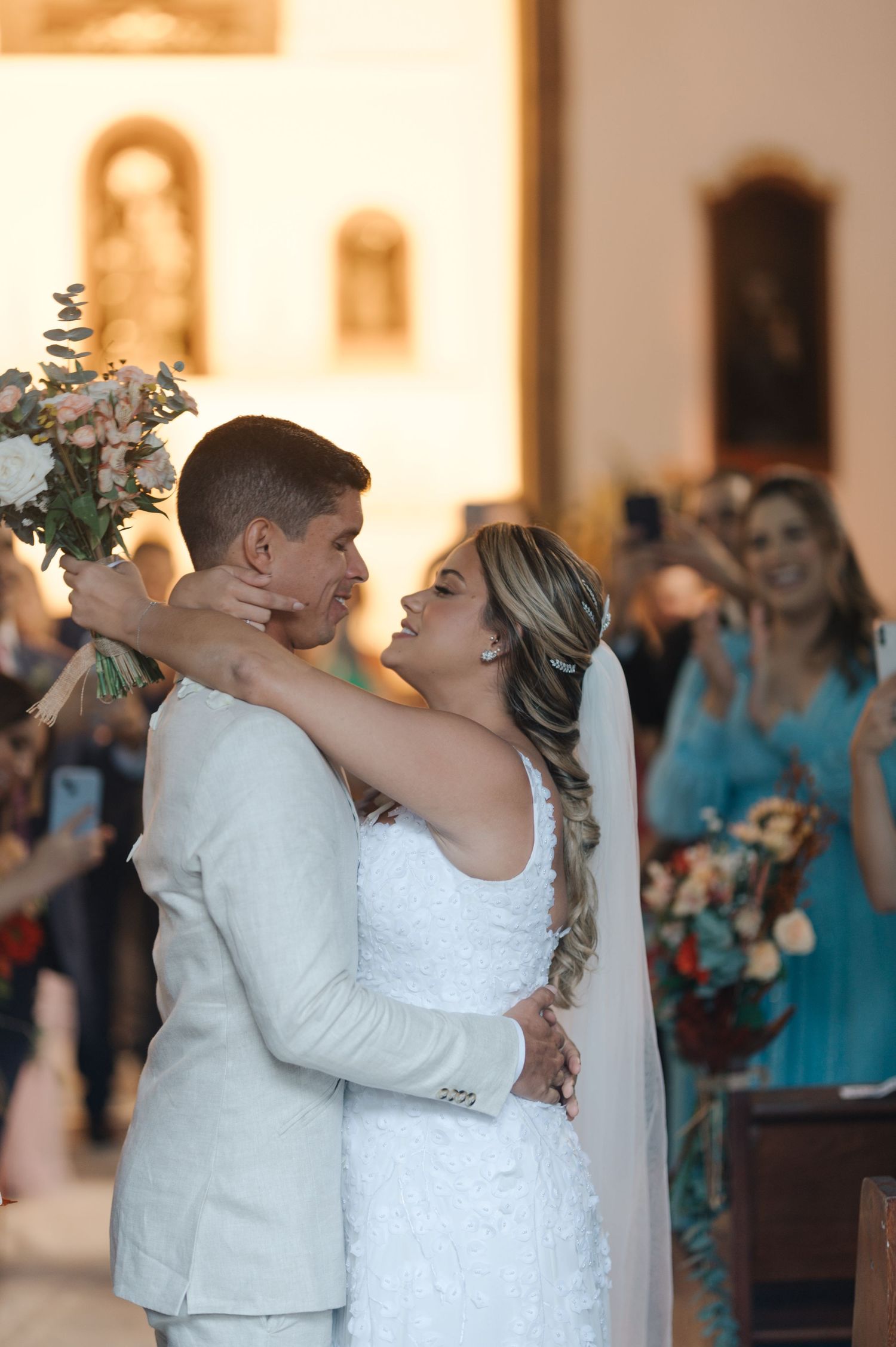 Newlyweds share a loving embrace during their wedding ceremony in a church setting.