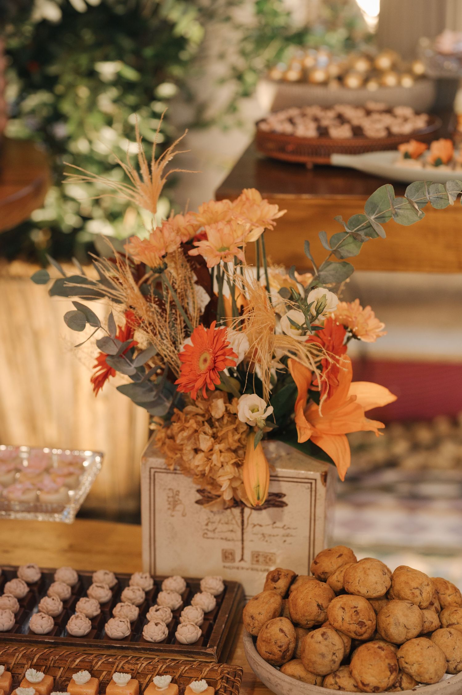 A decorative dessert table with orange lilies and cookies at a wedding reception.