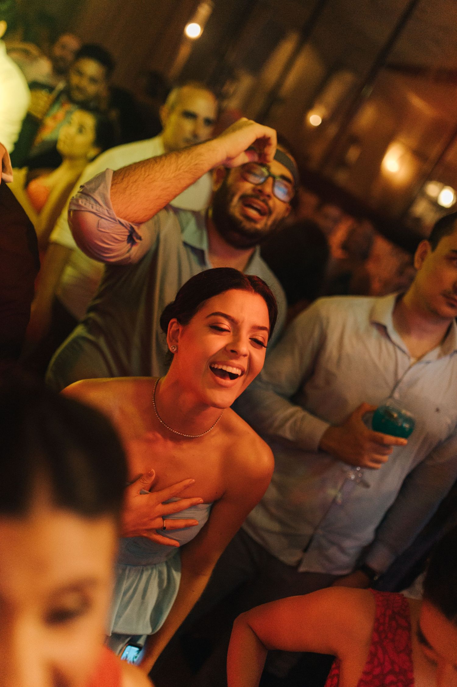 People laughing and celebrating at a lively indoor party with warm lighting.