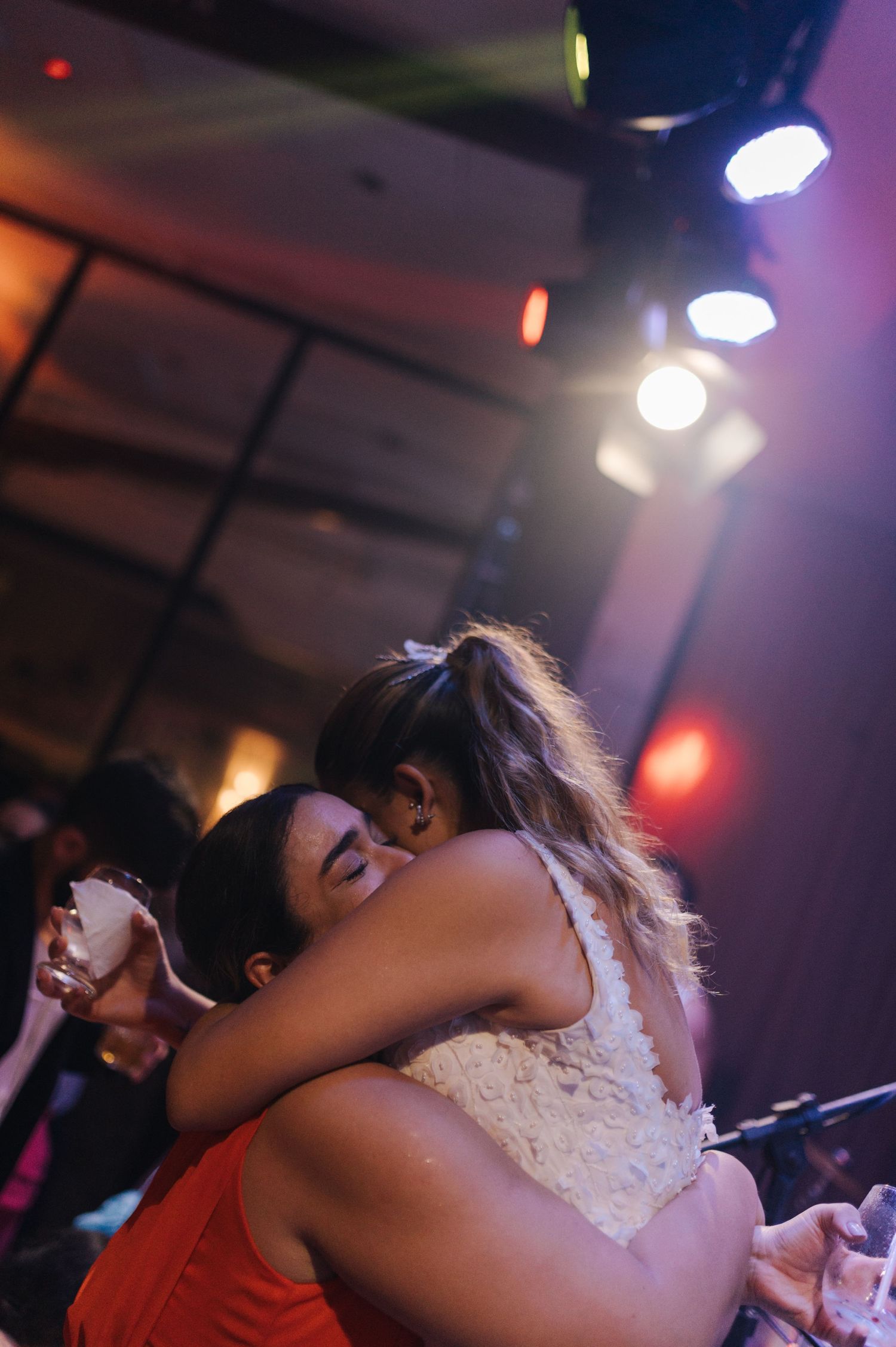 Two people embracing on a dark dance floor with colorful lighting.