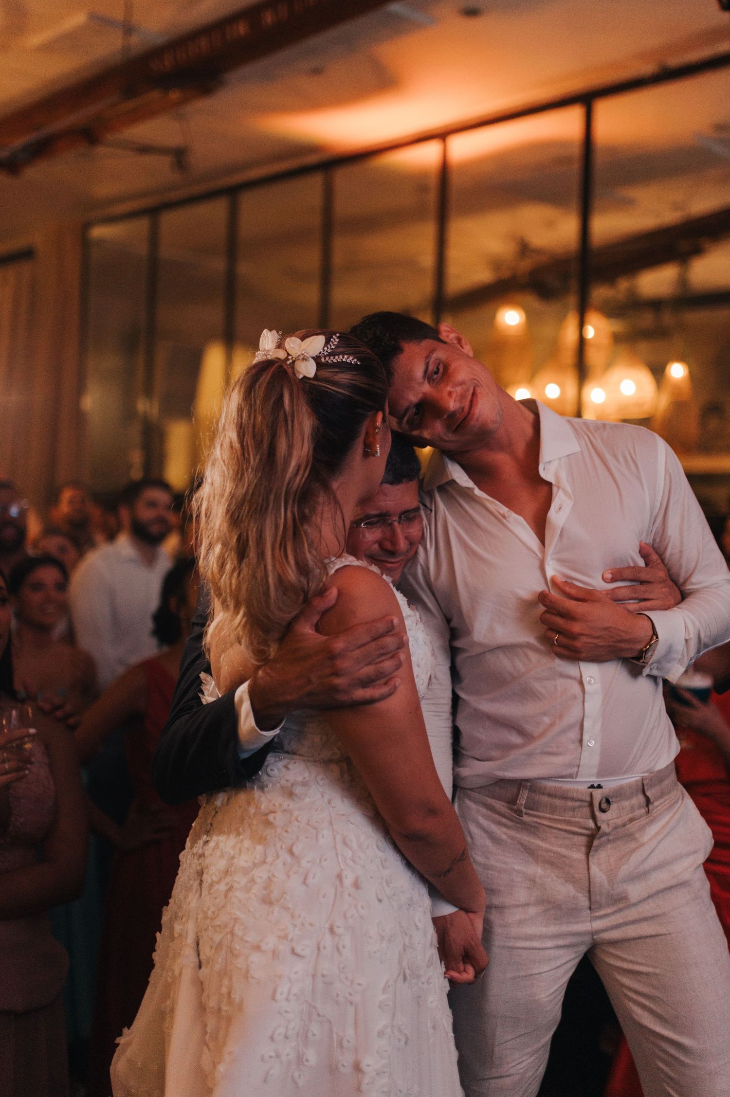 A couple shares a romantic dance moment at their wedding reception with warm lighting in the background.