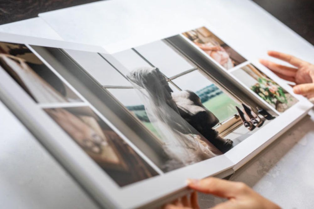 Someone looking at a wedding photo album with multiple printed photographs spread across pages.