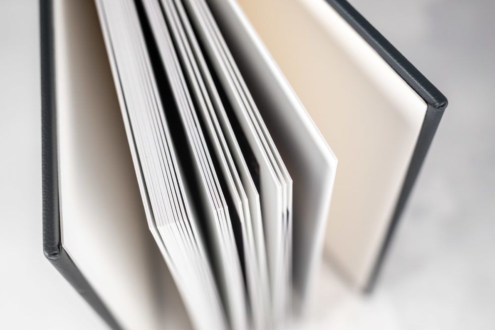Close-up view of white pages within an open book with black hardcover binding.