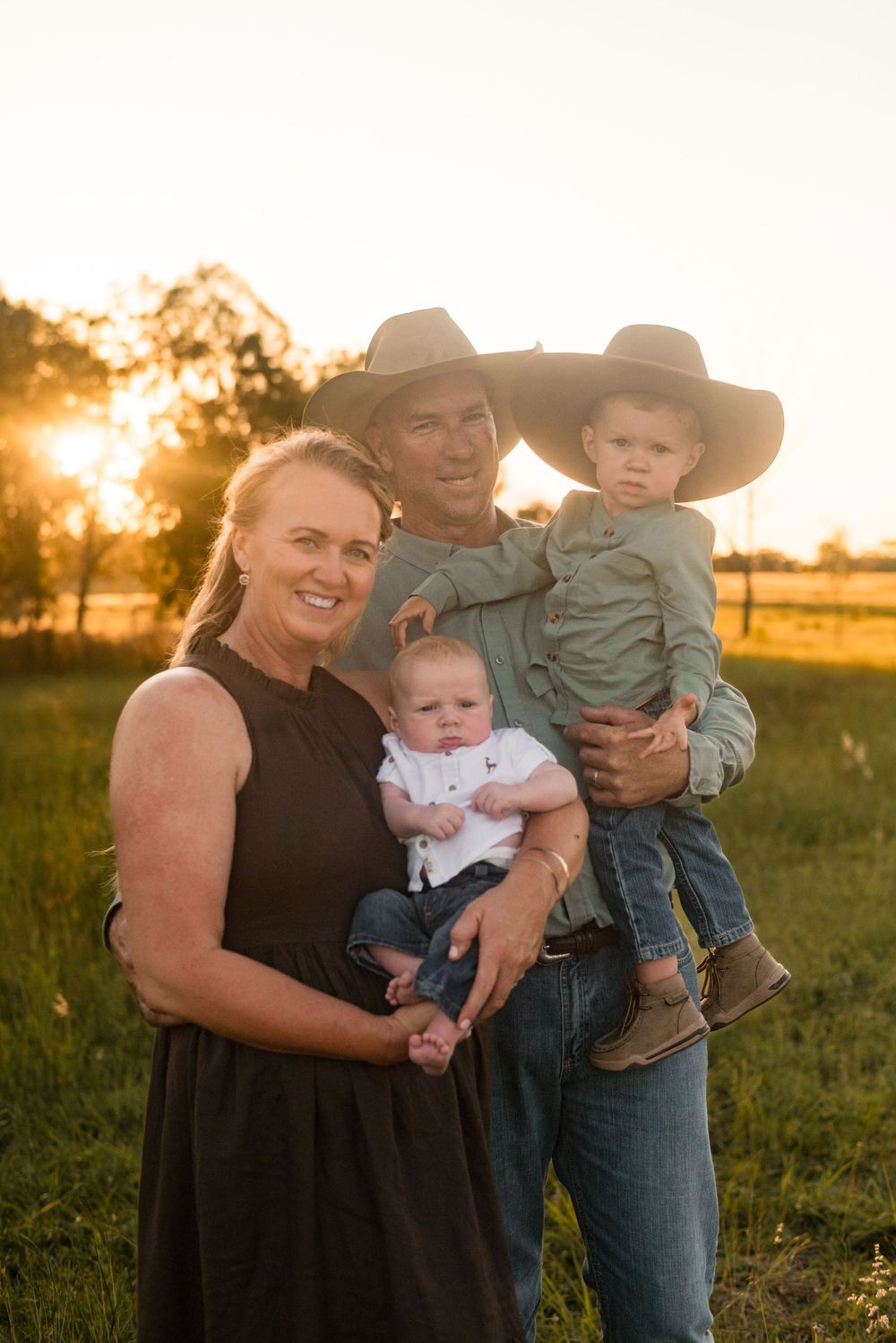 Rural family portrait with small children in a sunlit field.