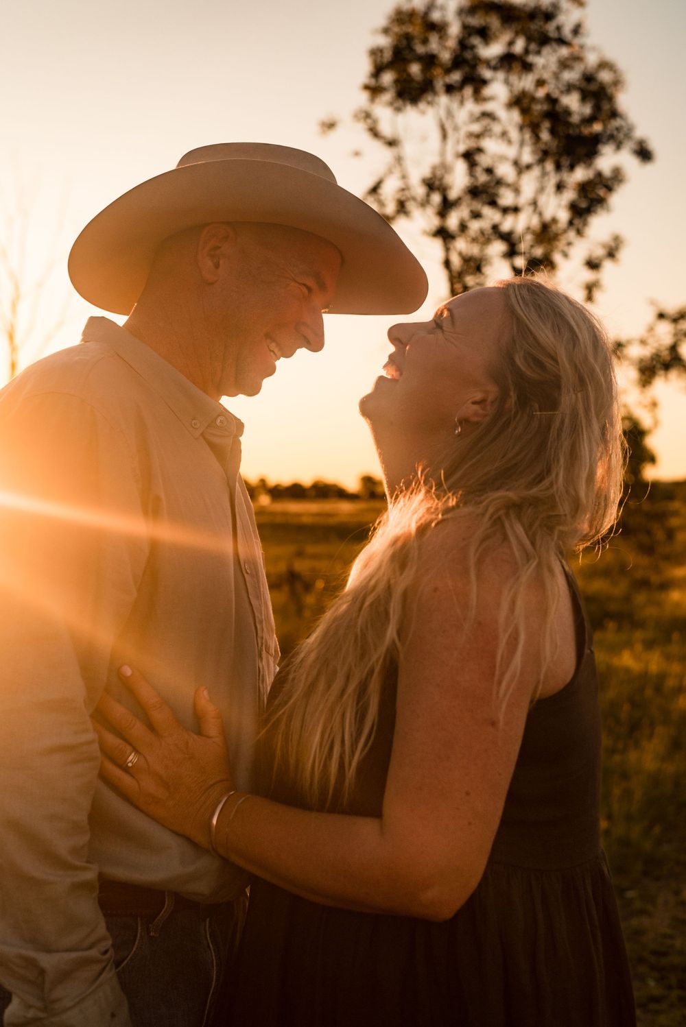 Romantic sunset portrait of couple laughing together in rural setting.