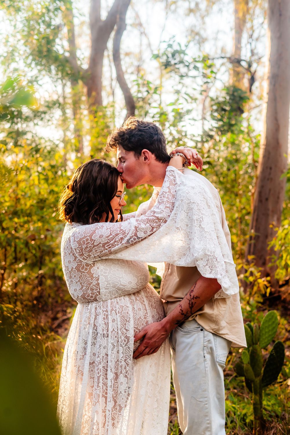 A romantic moment captured in golden sunlight among eucalyptus trees.
