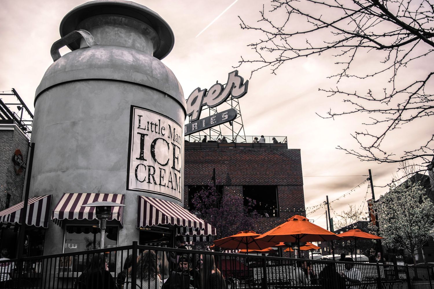 Giant ice cream cone shaped building with striped awning at twilight.