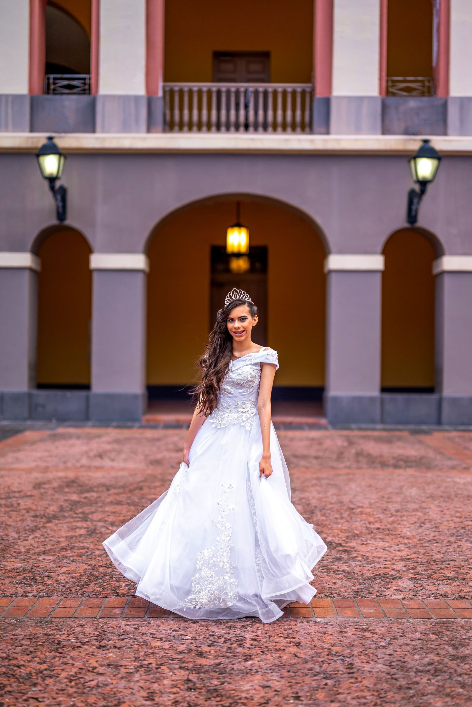 White wedding gown with lace details photographed in front of colonial architecture.