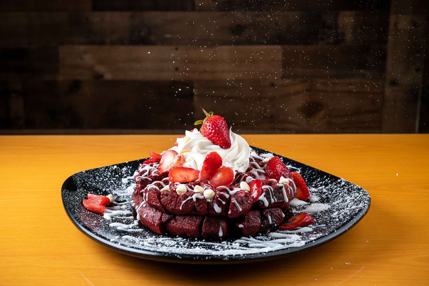 Chocolate dessert topped with whipped cream and fresh berries served on a decorative black plate.