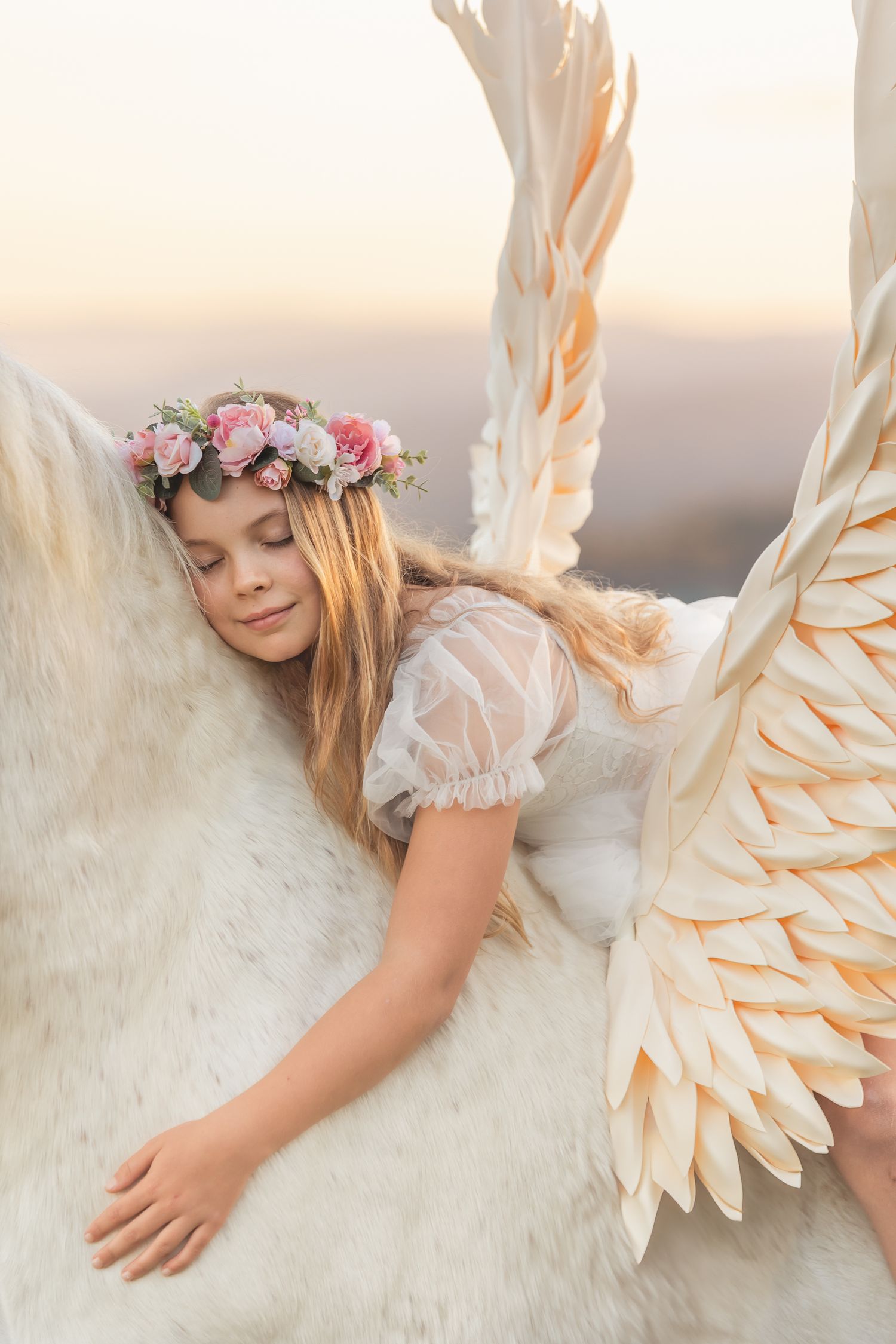 Whimsical close-up shot of white feathered wings and floral crown details.
