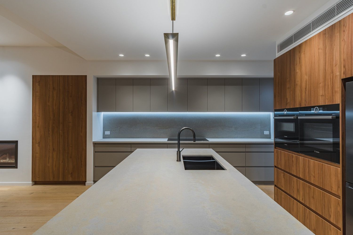 Sleek modern kitchen with wooden cabinetry, white countertops and blue LED backlighting.