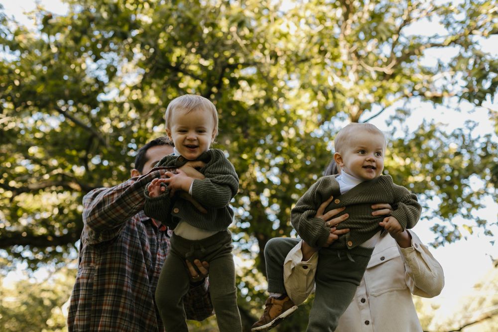 Family enjoying playful moments together in golden autumn sunlight.