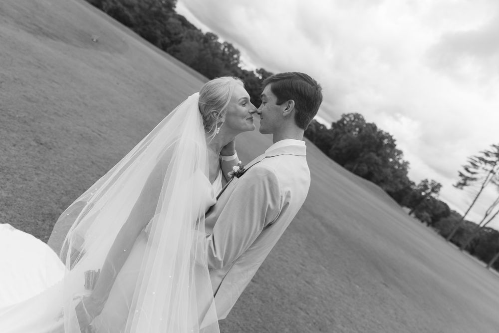 Romantic couple in wedding attire sharing intimate moments on a hillside.
