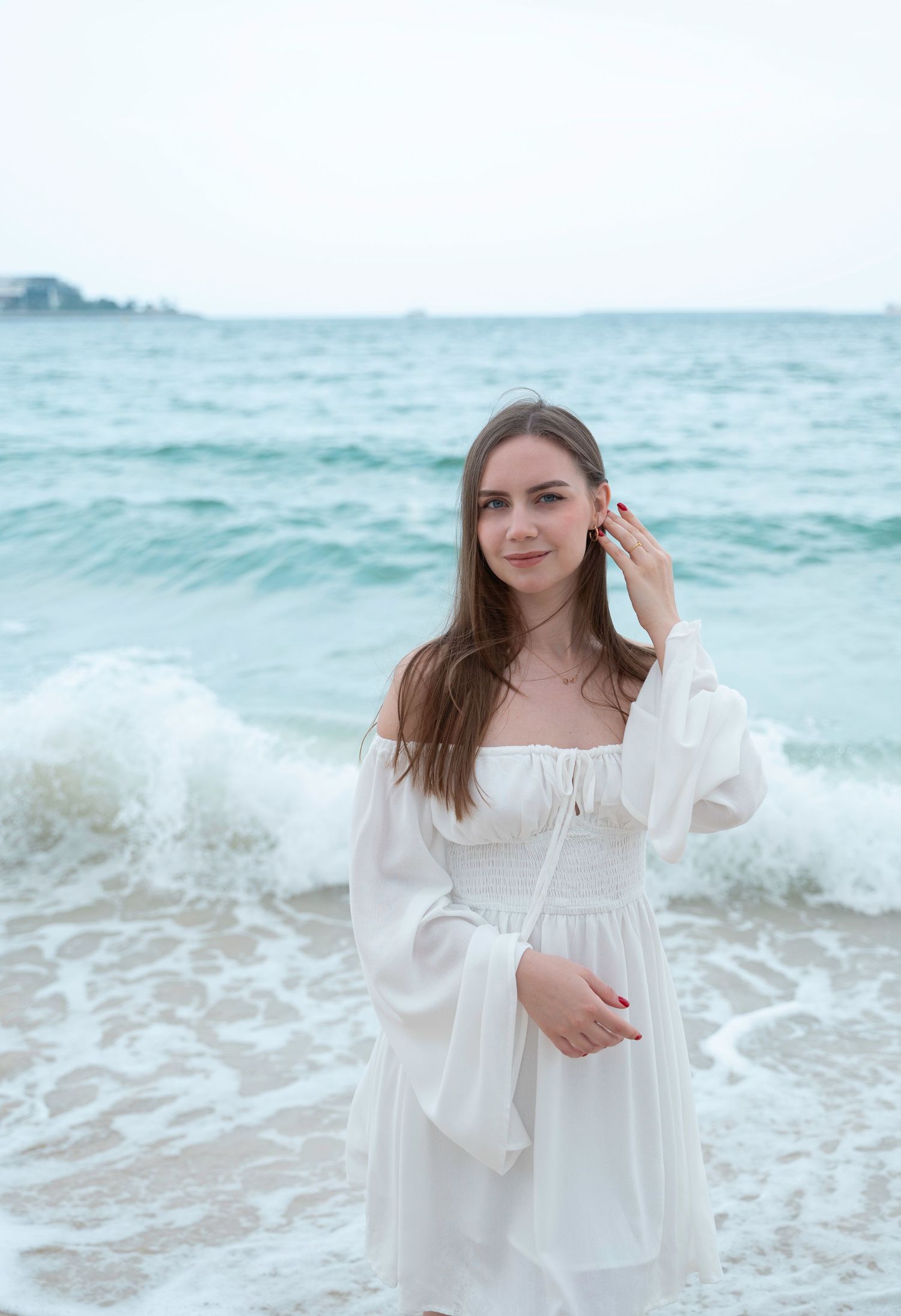 A young beautiful girl stands near the sea