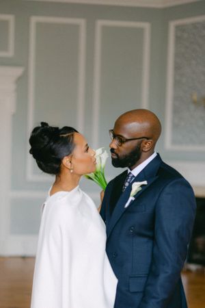 Romantic wedding portrait of couple sharing an intimate moment with white calla lily.