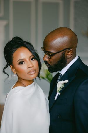 Elegant wedding portrait featuring a couple in formal attire, with the bride in white and groom in black suit.