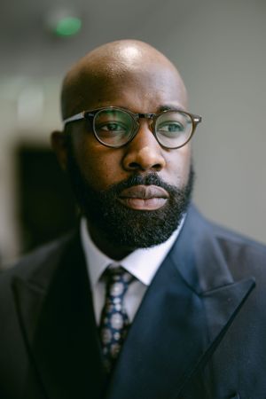Professional wearing glasses and a suit with a polished appearance.