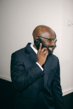 Person in business attire speaking on mobile phone indoors.