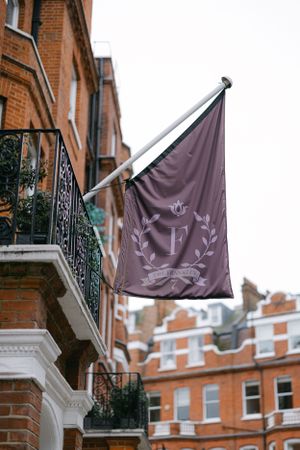 Purple flag with elegant monogram design hanging from brick building balcony.