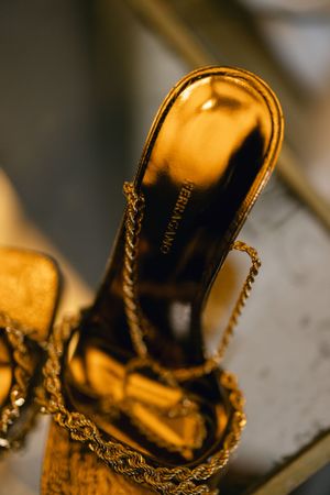 Close-up of a golden metallic high heel shoe with chain detail.