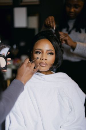 Professional makeup application in progress with white robe and beauty tools.