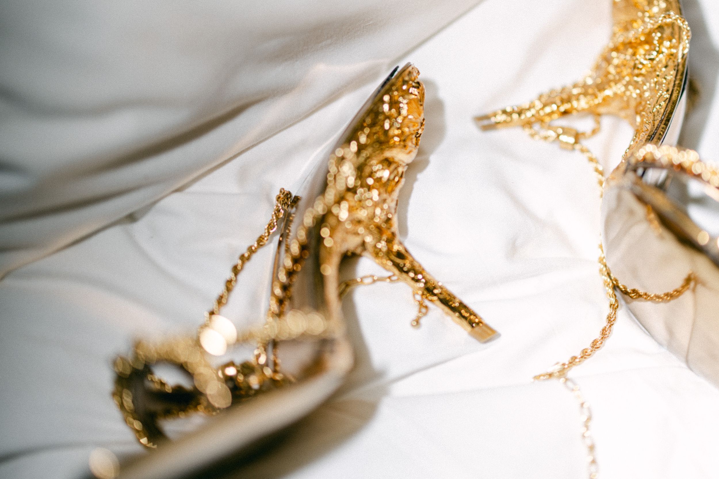 Close-up of sparkly gold wedding heels with decorative chain details.
