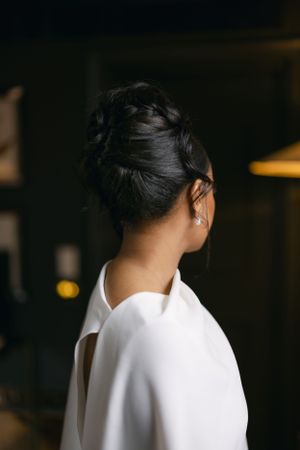 Close-up side view of elegant bridal updo hairstyle and white dress.