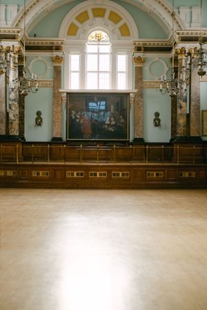 Grand historic hall with ornate turquoise walls, arched ceiling, and wooden benches.