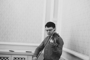 Musician plays violin in formal performance setting.